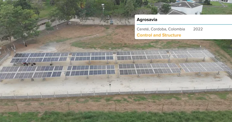 Instalación de paneles solares en un campo verde con montañas al fondo durante el atardecer