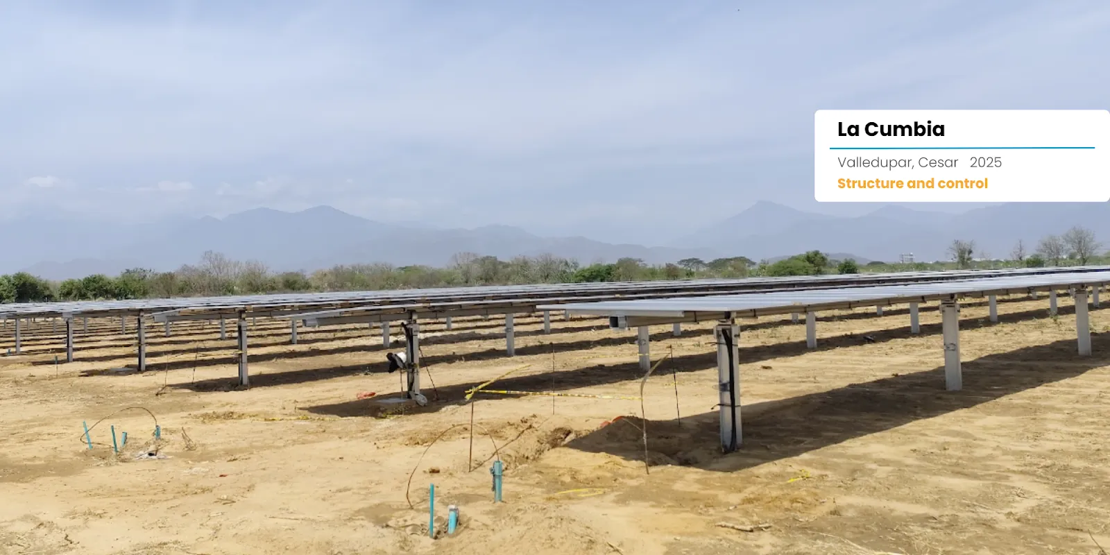 Instalación de paneles solares en un campo verde con montañas al fondo durante el atardecer