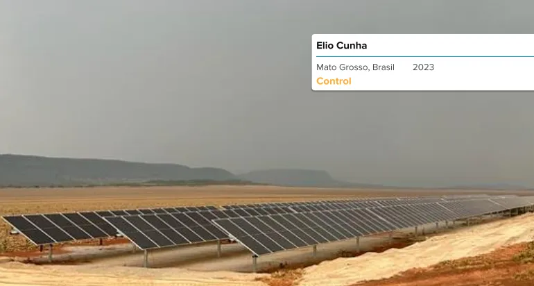 Instalación de paneles solares en un campo verde con montañas al fondo durante el atardecer