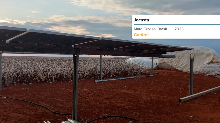 Instalación de paneles solares en un campo verde con montañas al fondo durante el atardecer