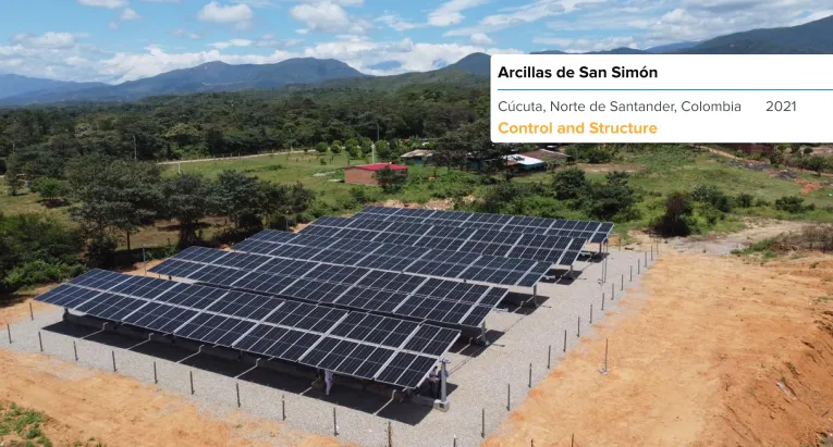 Instalación de paneles solares en un campo verde con montañas al fondo durante el atardecer